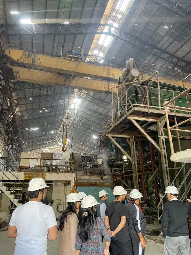 Rombongan berhelm proyek meninjau lantai pabrik