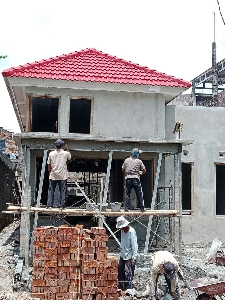 Pekerja memplester rumah dua lantai beratap genteng merah